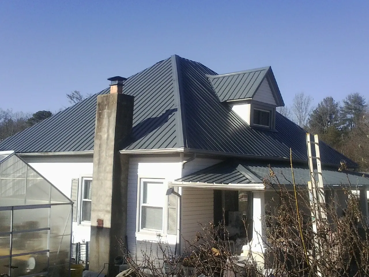 Dark blue standing seam metal roof on a white farmhouse with dormer — Slate & Tile Roof Repair by Roofing Brothers in Willamina