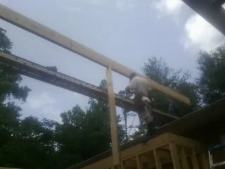 Carpenter setting a ridge beam over a new addition frame — Ice Dam Removal by Roofing Brothers in Willamina