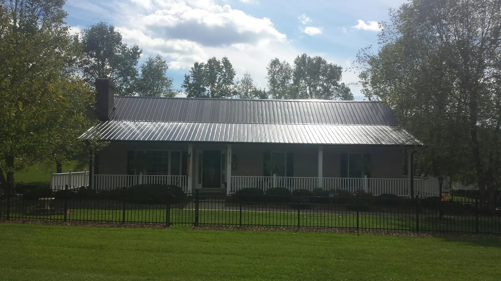 Gray metal roof on a brick ranch with a full width front porch — Gutter Guard Installation work by our crew in Willamina