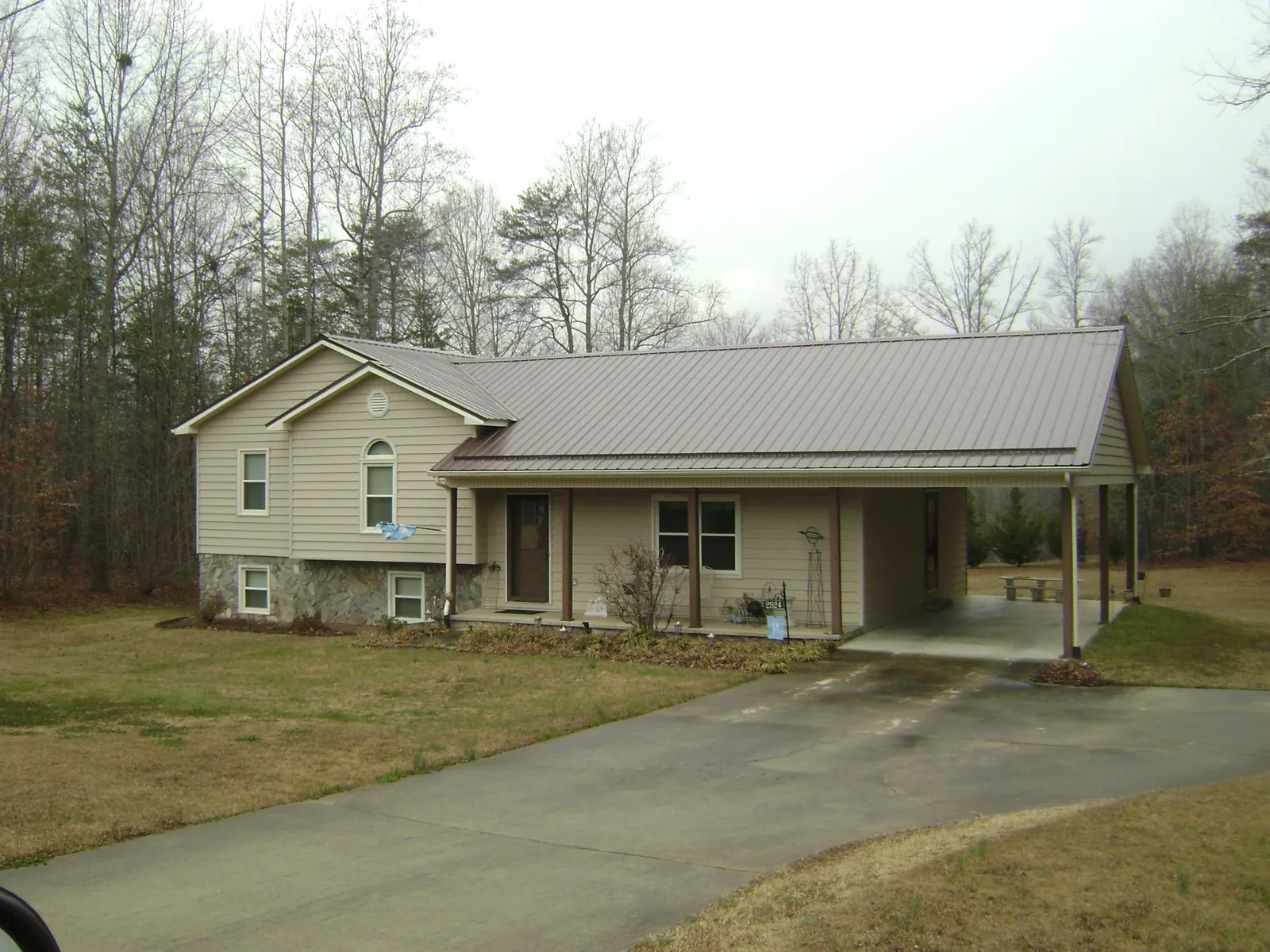 Brown metal roof on a tan split level home with an attached carport in Willamina